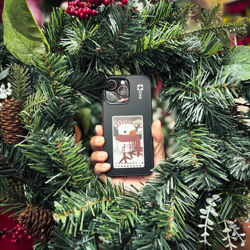 Black TIZAG Digital Canvas Case with a snowman design held in hand surrounded by a festive Christmas wreath.